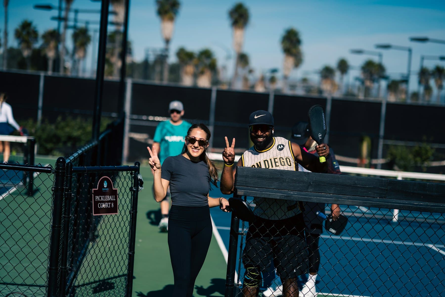Friends smiling at the net after a pickleball game